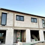 Nowe domy na sprzedaż w Głogowie – etap budowy inwestycji mieszkaniowej z zamontowanymi oknami i przygotowaną bryłą budynku