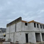 Budowa nowoczesnych domów na sprzedaż w Głogowie – inwestycja mieszkaniowa na etapie wznoszenia górnej kondygnacji i przygotowania konstrukcji dachu