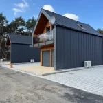 Nowoczesny budynek mieszkalny z ciemną elewacją, drewnianym wykończeniem i balkonem
